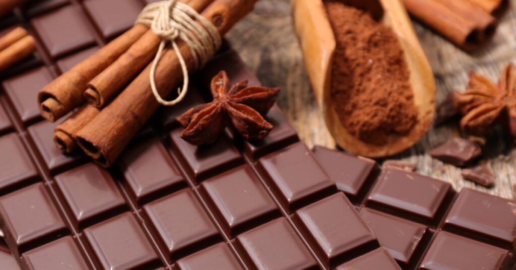 Pedaços de chocolate amargo 70% cacau e canela em pó como alternativas saudáveis para controlar a vontade de doce.