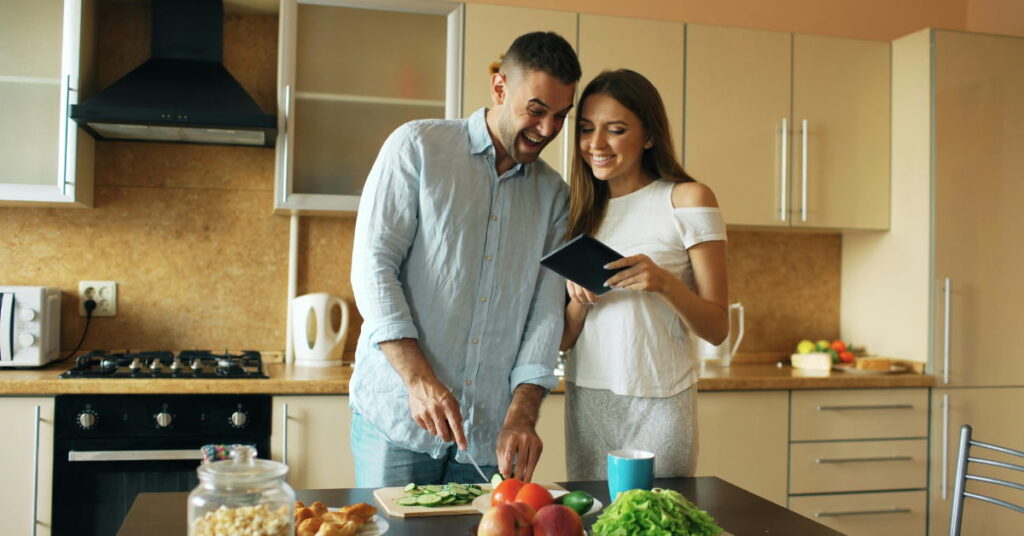 Casal cozinhando junto um jantar saudável de Dia dos Namorados em casa para manter a dieta.