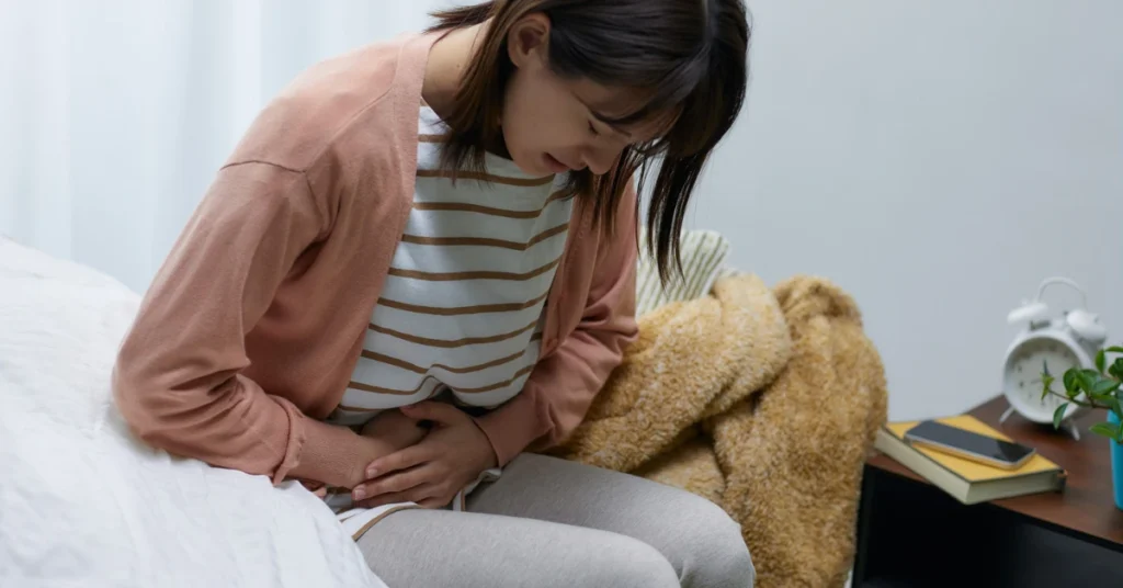 Mulher com desconforto abdominal e se perguntando por que sente a barriga inchada depois de comer.