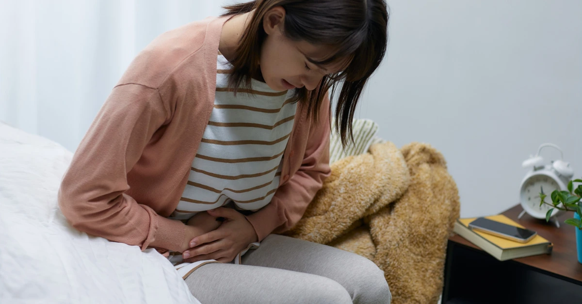 Mulher com desconforto abdominal e se perguntando por que sente a barriga inchada depois de comer.