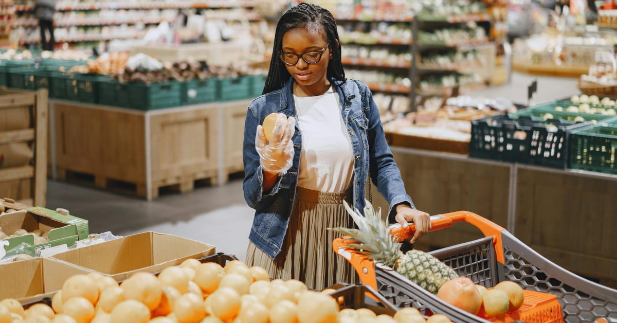 Mulher escolhendo frutas e vegetais baratos na feira para economizar na dieta.