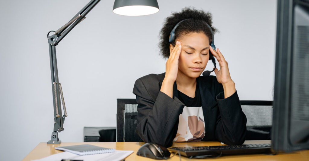 Mulher estressada no trabalho sofrendo com cortisol alto e bloqueio no emagrecimento.