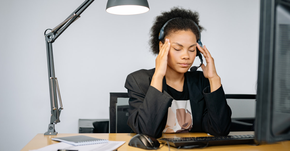 Mulher estressada no trabalho sofrendo com cortisol alto e bloqueio no emagrecimento.