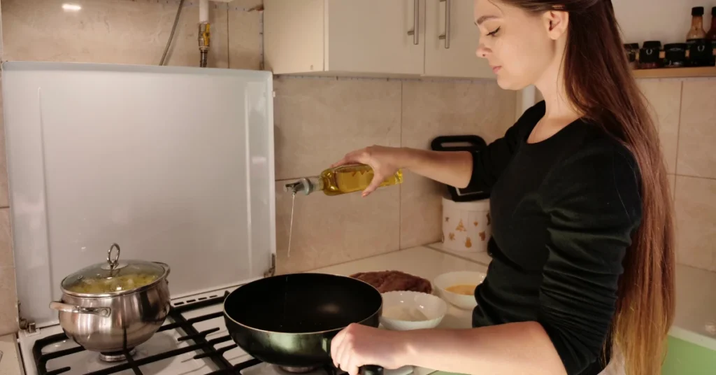 Mulher usando azeite sem mensurar, dificultando o processo de emagrecimento.