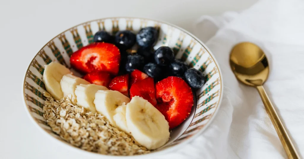 Como aumentar o consumo de fibras: tigela com aveia, frutas frescas e sementes ricas em fibras.