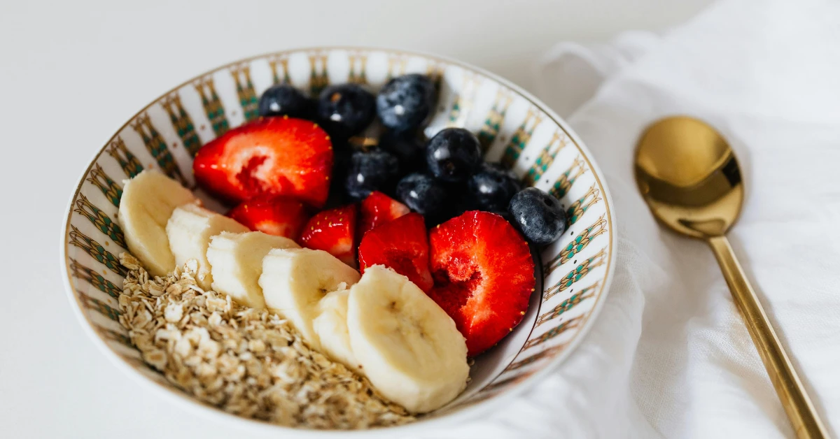 Como aumentar o consumo de fibras: tigela com aveia, frutas frescas e sementes ricas em fibras.