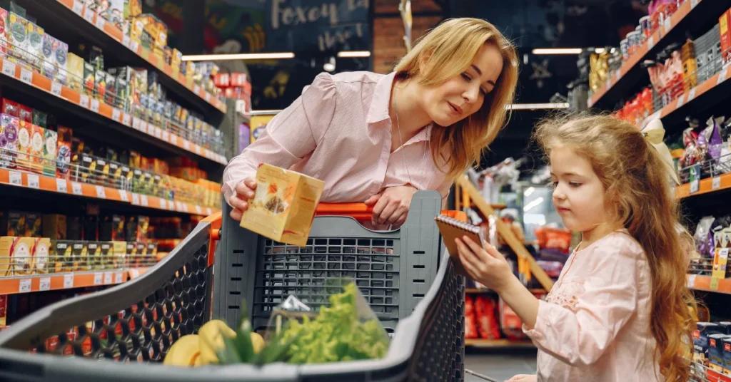 Como ler rótulos de alimentos: mulher analisando a embalagem de um produto no supermercado.