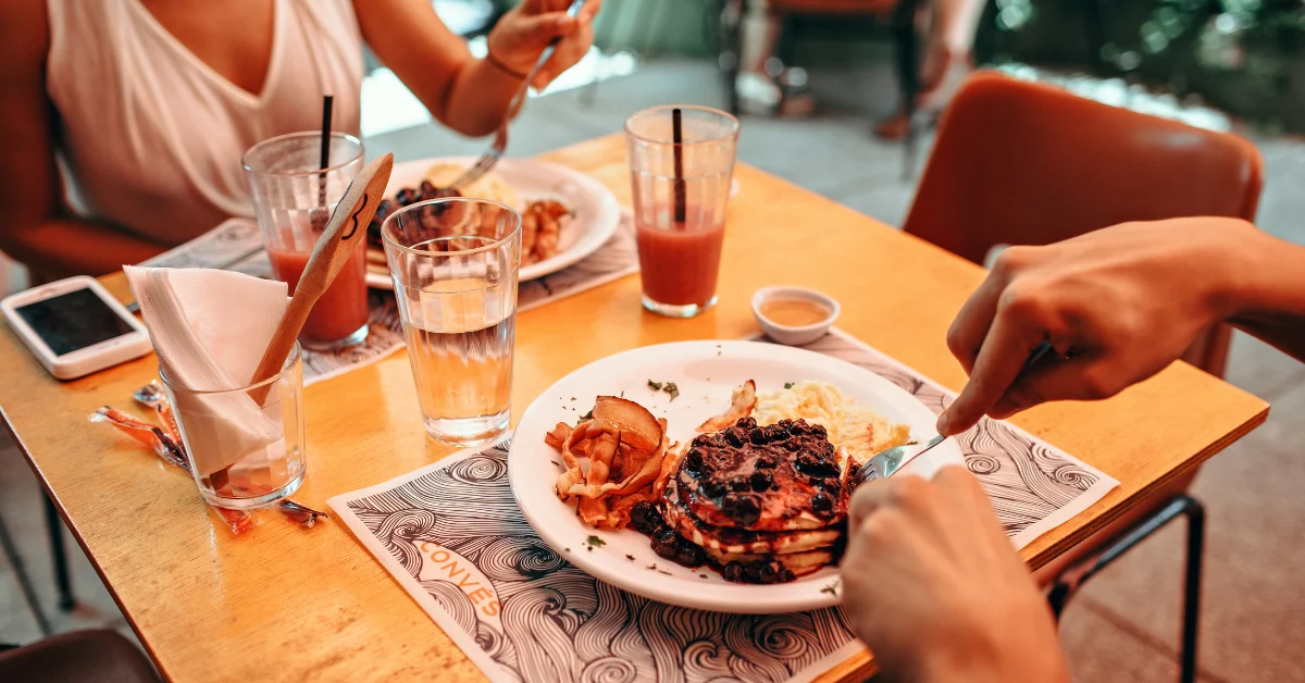 Como comer em restaurantes sem sair da dieta: mulher jantando com amigos em um restaurante.