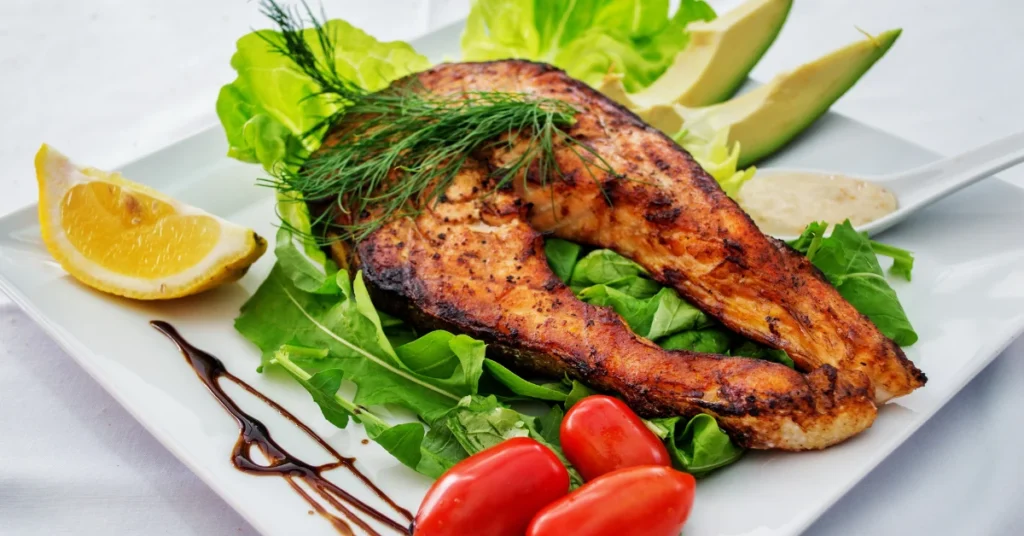Como comer em restaurantes sem sair da dieta: prato equilibrado com grelhado e vegetais.